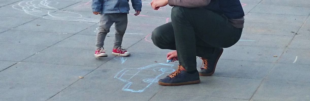 Niña y su padre dibujando en la calsada