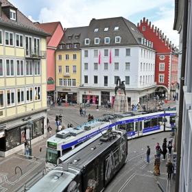 Imagen del Curso de Gestión de Movilidad Sostenible y Segura. Dos tranvías se cruzan circulando por el centro de una ciudad europea.